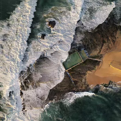 Aerial photograph of Mona Vale ocean pool on Sydney's Northern Beaches, white surf breaking over the rock shelf around aqua …