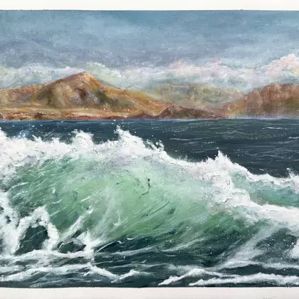 A translucent wave breaks with mountains in the background.