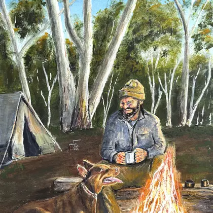 A lone Australian bushman sits by a large campfire with his faithful Kelpie dog. In the background the sun is setting on a g…