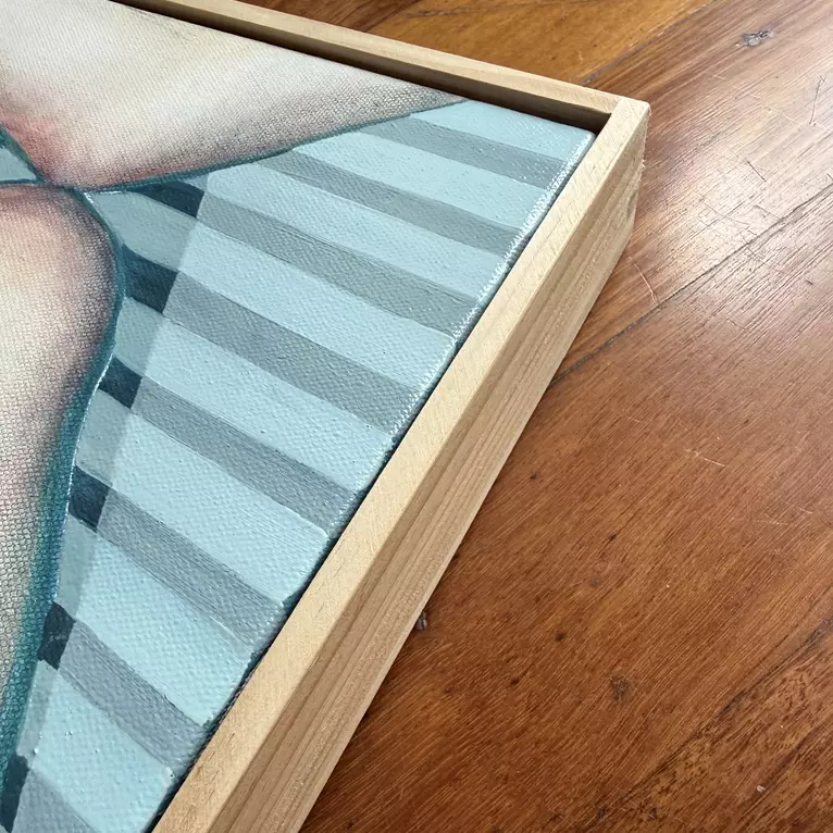 A framed painting of nude legs crossed, one over the other, with soft skin tones. Blue-grey and white horizontal… — edge view