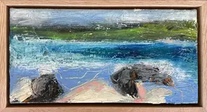 An abstract seascape with the with pale sandy area, beach rocks and the blue ocean and green headland