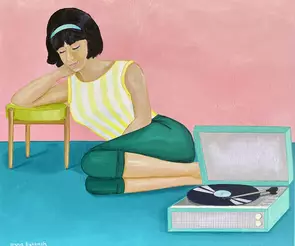 Young woman reclining on floor listening to an album on record player.