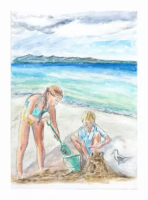 Children build sand castles on the beach with the sea and mountains in the background