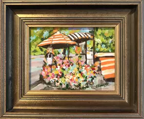 Flower seller under an umbrella selling flowers from a stall.
