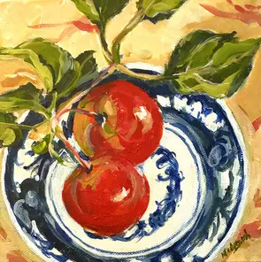 Red apples and green leaves on a blue and white plate.