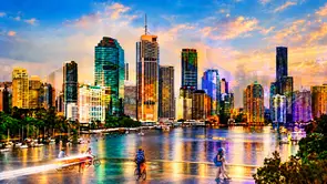 ""Brisbane in Motion"' A panoramic view of Brisbane’s skyline at sunset, with gold and turquoise light reflected across the …