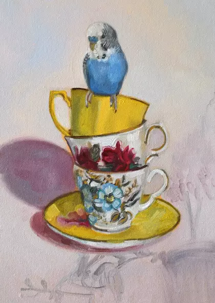 A blue budgie sits on a stack of brightly coloured vintage tea cups