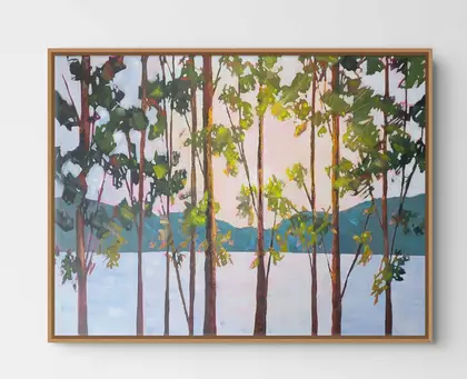 Sunset on water through the leaves of trees . peach and pink colours with the greens of trees