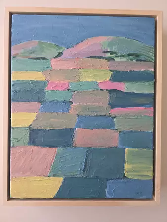 Coloured fields in pastel tones with mountains in the background. — shown hanging